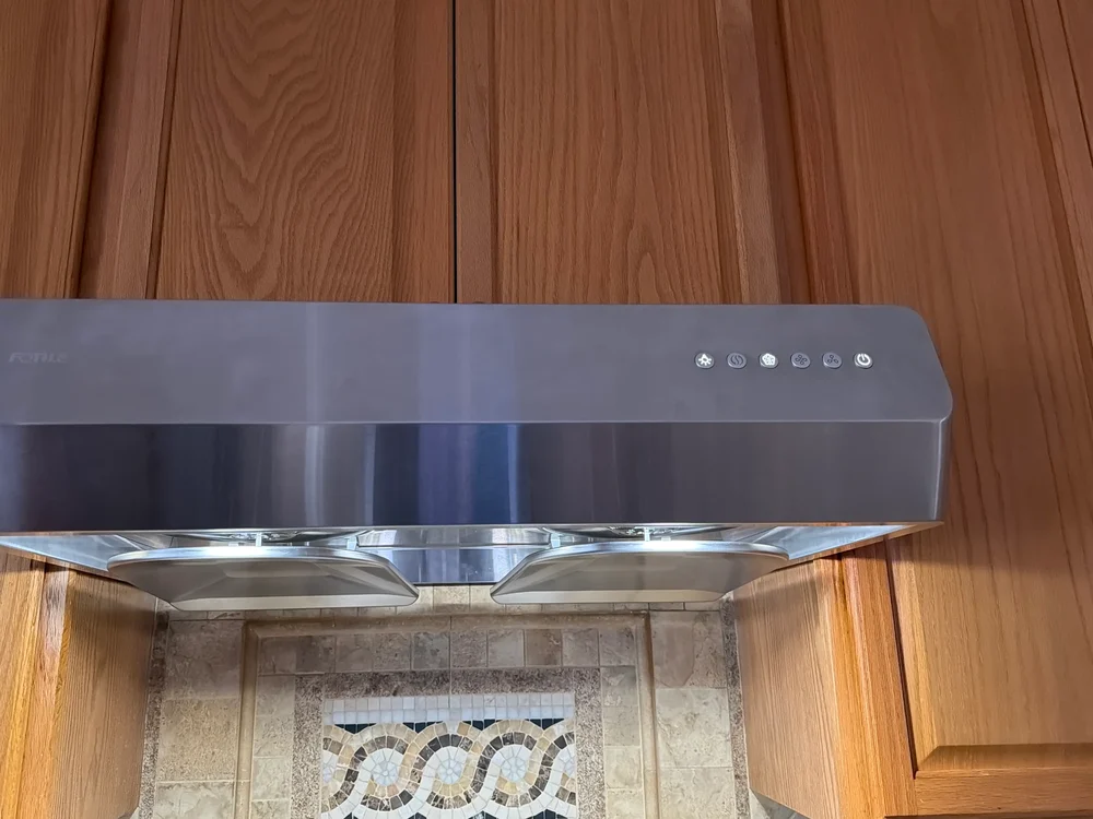 Stainless steel under-cabinet range hood installed in a kitchen